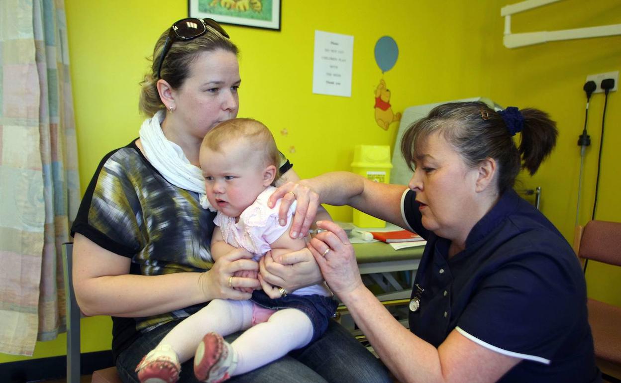 Una madre lleva a su hija de 14 meses a que se vacune contra el sarampión