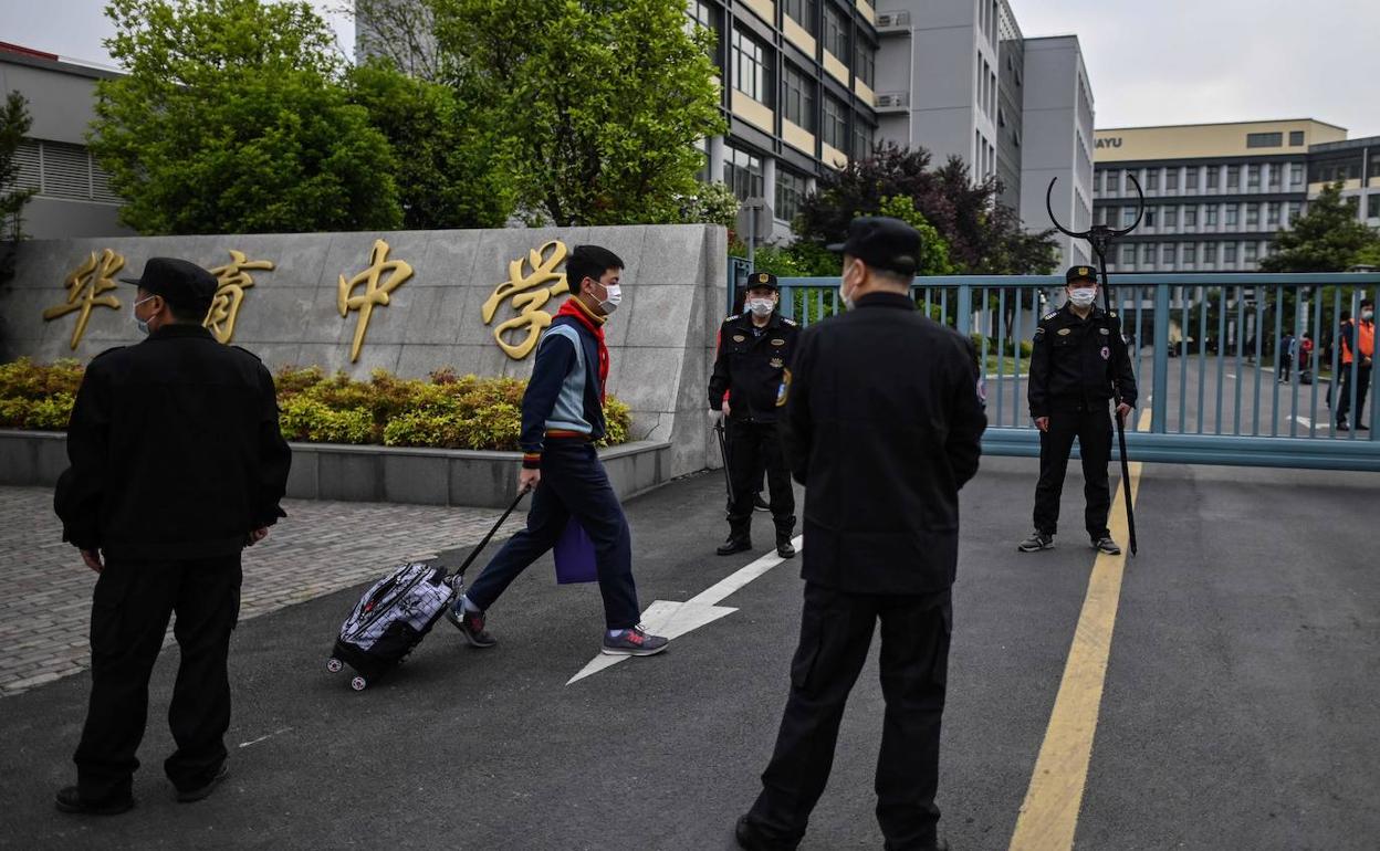 Un estudiante protegido con mascarilla llega a un instituto en Shanghái