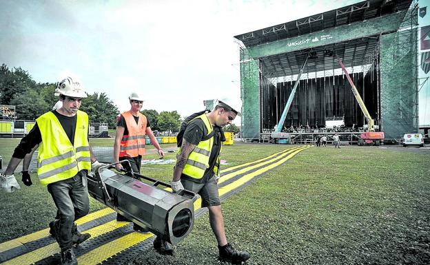 Técnicos trasladan un foco durante el montaje de un festival.