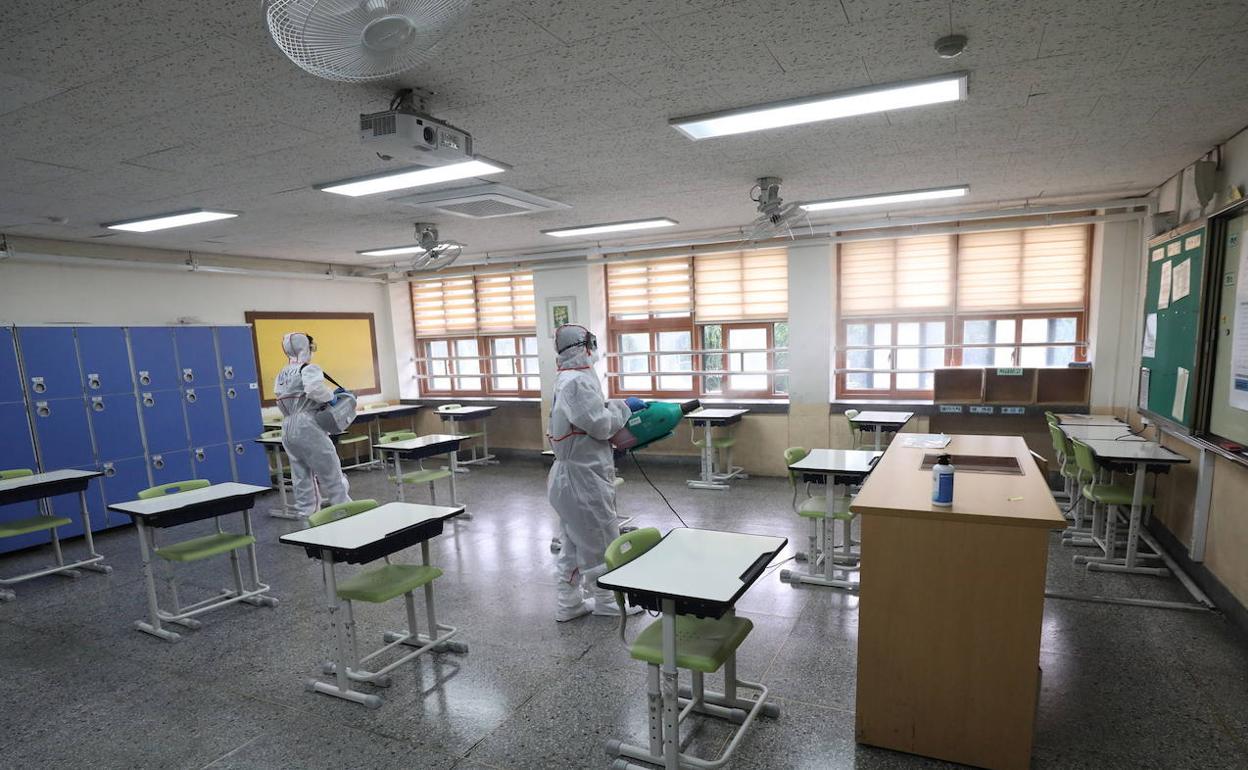 Varias personas desinfectan un aula de un colegio en Corea del Sur. 