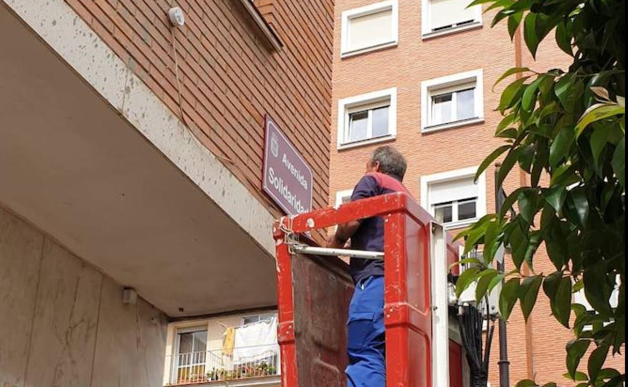 Uno de los operarios pone la nueva placa en la calle Solidaridad, antes Jorge Vigón. 