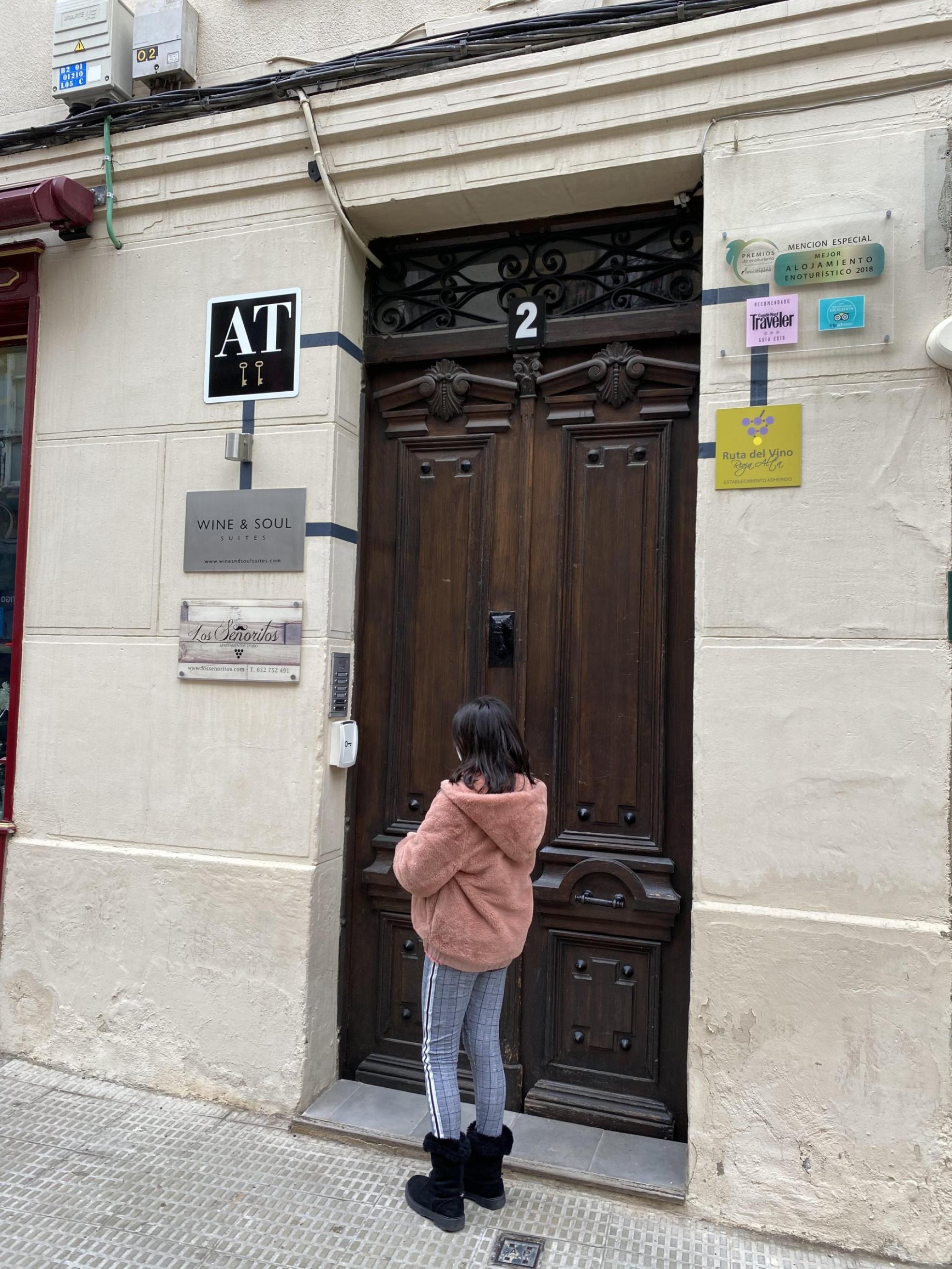 Una pequeña se acerca a un edificio que alberga pisos turísticos. 
