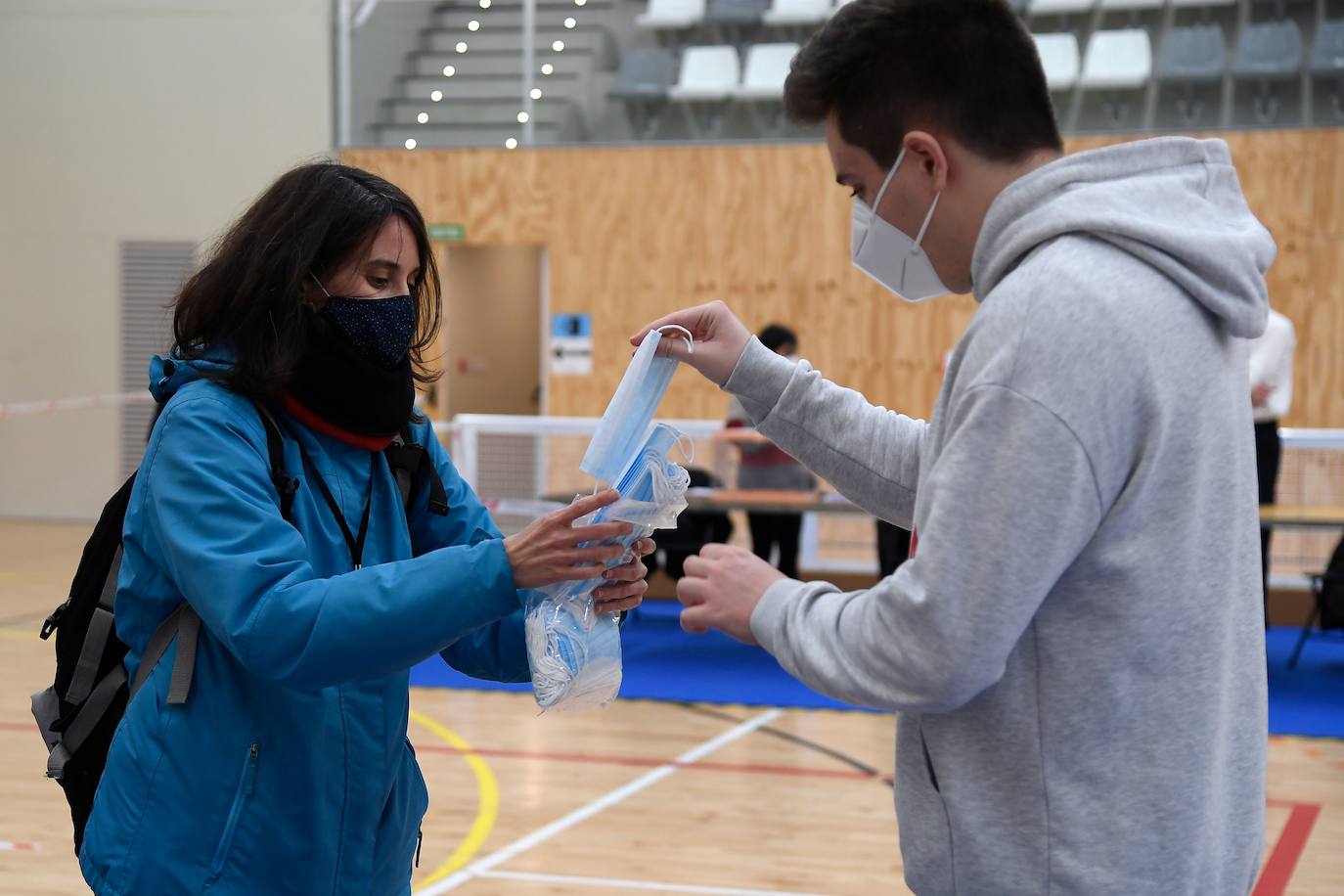 Un miembro de seguridad reparte mascarillas en un colegio electoral. 