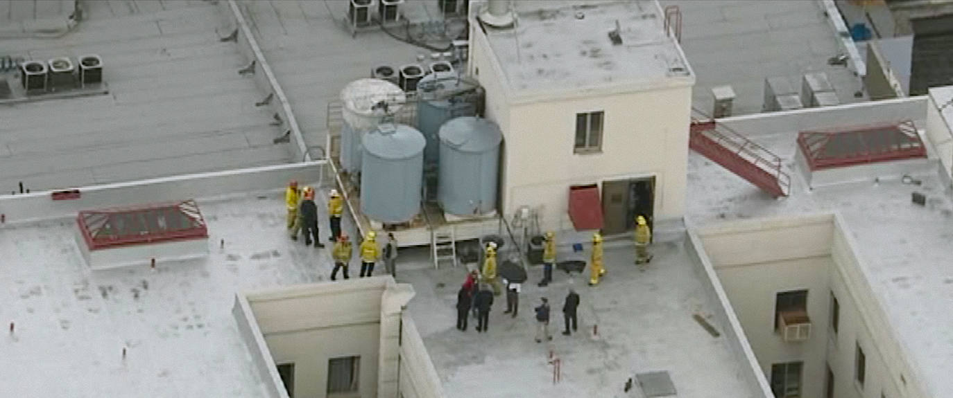 Agentes de Policía y bomberos, en la azotea del edificio, delante de los tanques donde se encontró el cadáver.