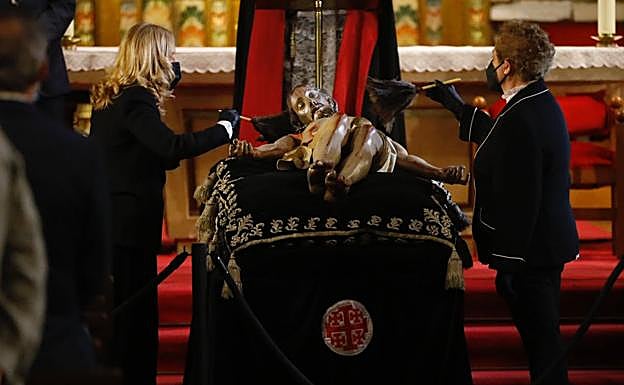 Dos mujeres limpian el Cristo. 