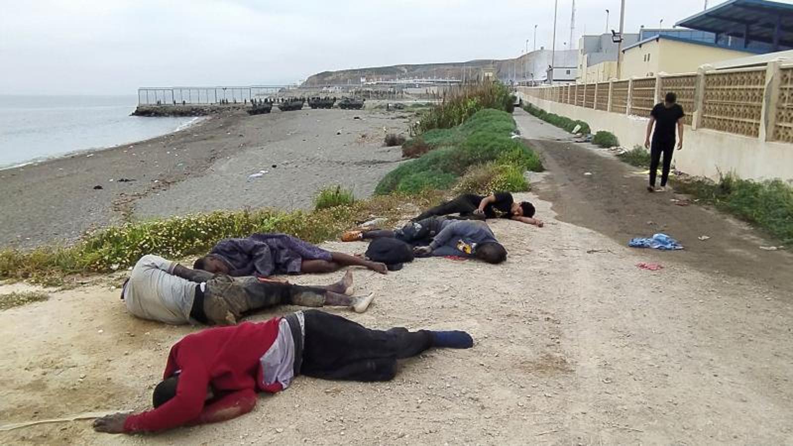 Un grupo de inmigrantes descansa tras su llegada este martes a uno de los espigones fronterizos de Ceuta.