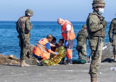 Imagen secundaria 1 - Brahim, en el centro, a su llegada a la playa del Tarajal (arriba), varios inmigrantes asistidos por el Ejército y Cruz Roja.