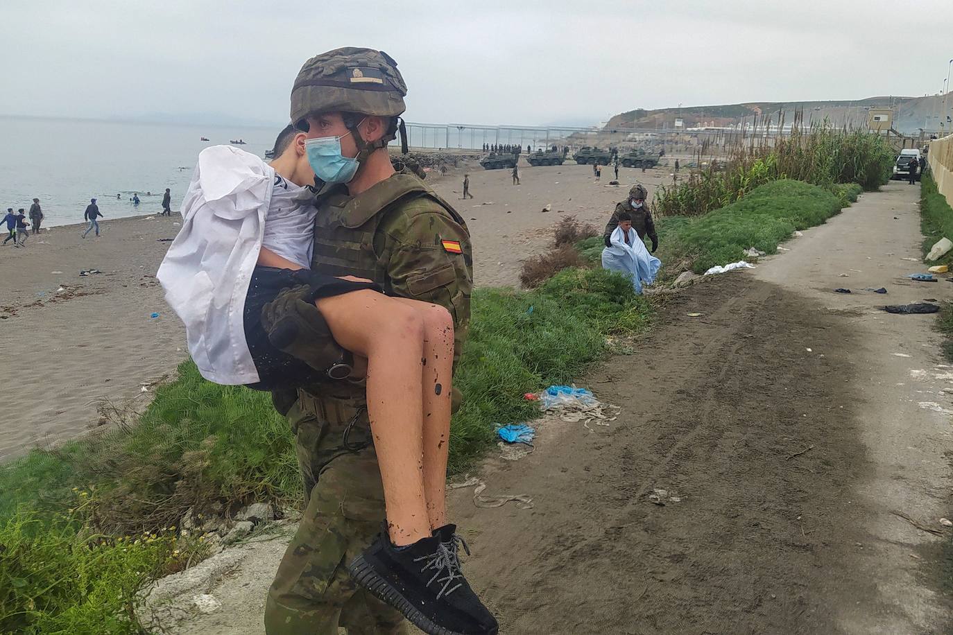 Un soldado español lleva en brazos a un menor marroquí durante la masiva entrada de inmigrantes por la frontera de Ceuta, a través del paso entre Castillejos y El Tarajal. 