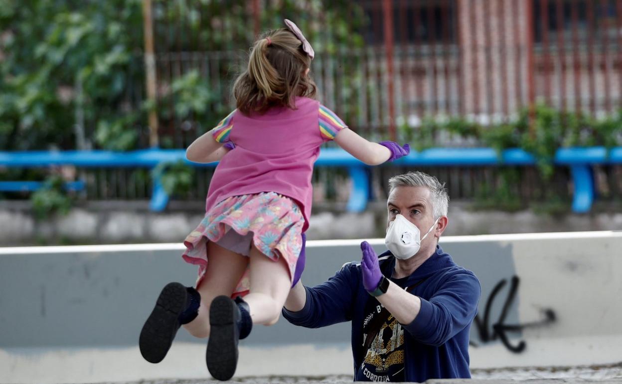 Un padre juega en el parque con su hija. 