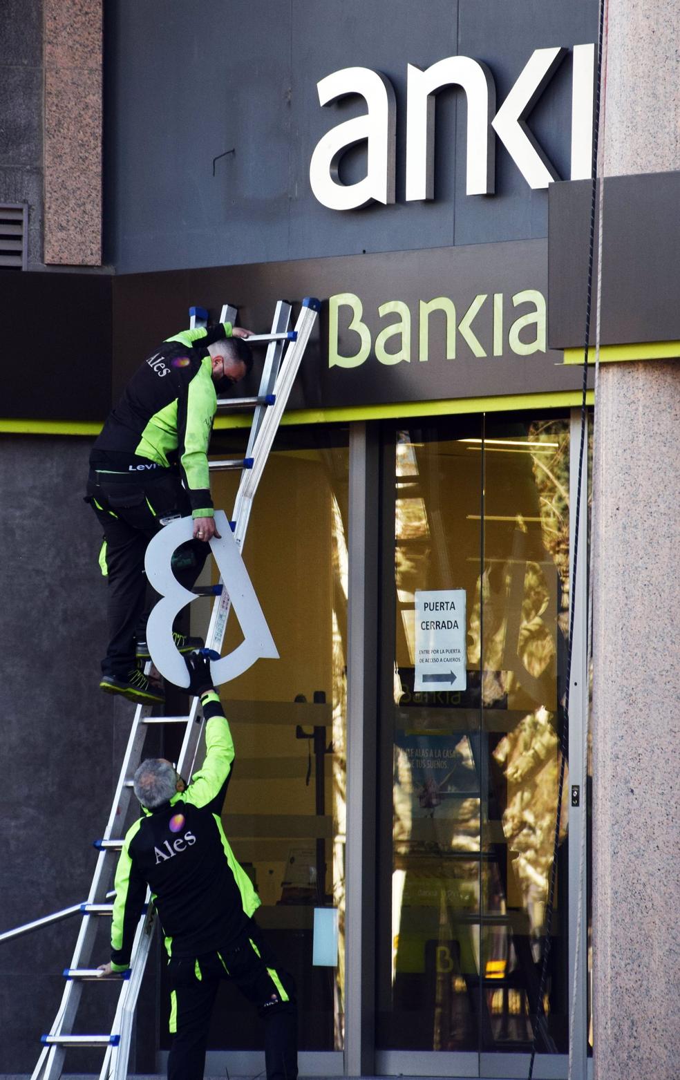 Los operarios retiran los letreros de Bankia de la sede principal de Logroño. 