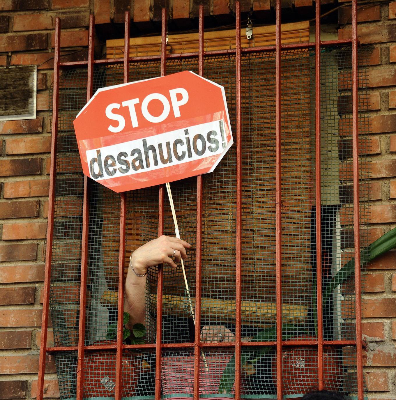 Una mujer sostiene un cartel de «Stop Desahucios» en una vivienda de Madrid. 