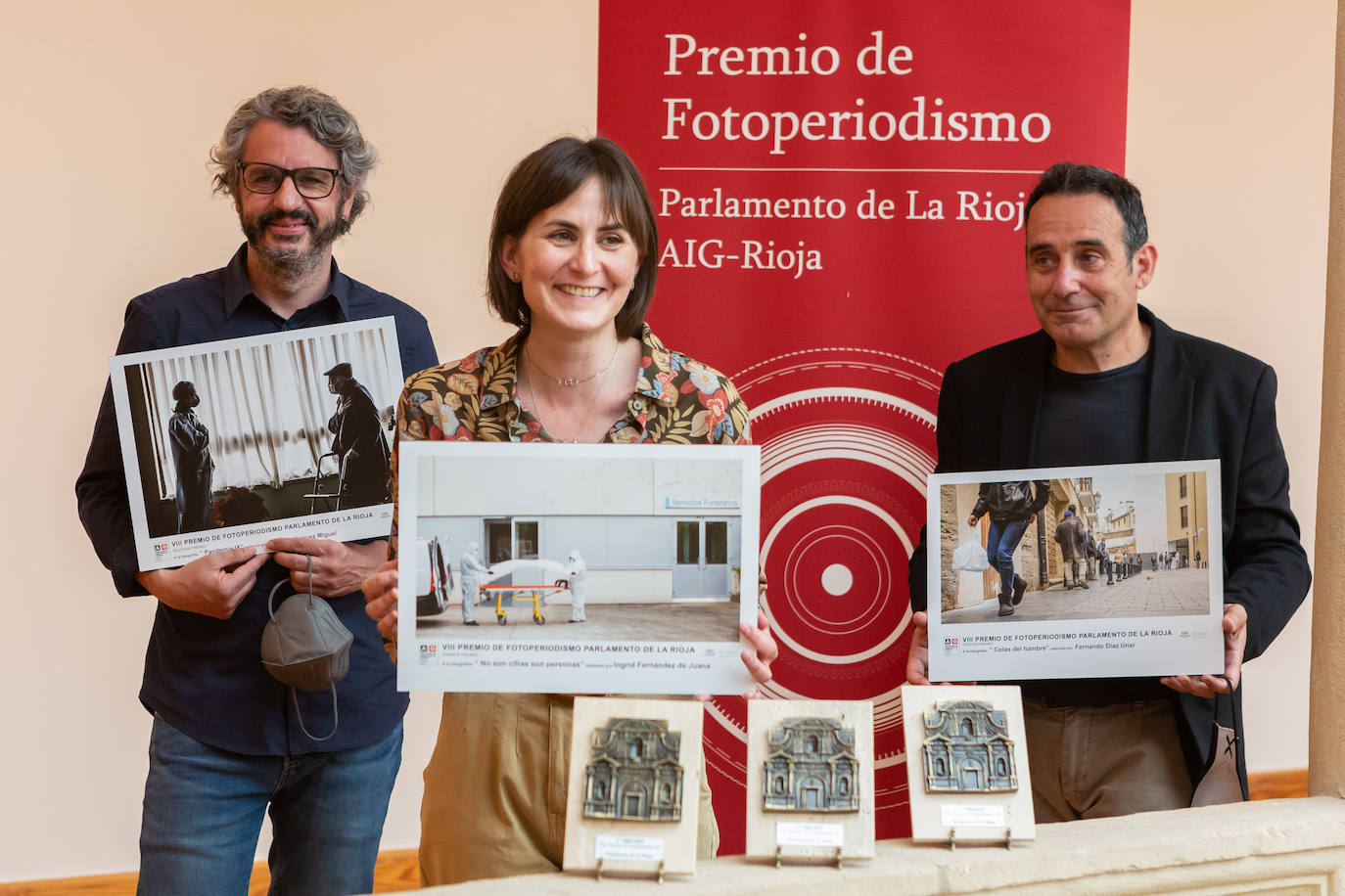 Los tres fotógrafos premiados posan con sus imágenes. 