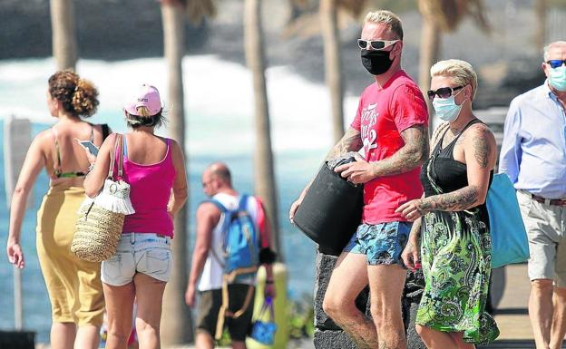 Personas con mascarilla en la playa..