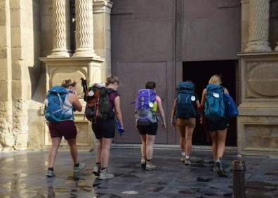 Imagen secundaria 1 - Arriba, salida desde el Puente de Piedra y, abajo, unas peregrinas alemanas que se han sumado al grupo entran en la iglesia de Santiago, momento en el que Pablo Hermoso de Mendoza cruza el Arco del Revellín. 