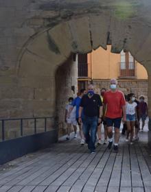 Imagen secundaria 2 - Arriba, salida desde el Puente de Piedra y, abajo, unas peregrinas alemanas que se han sumado al grupo entran en la iglesia de Santiago, momento en el que Pablo Hermoso de Mendoza cruza el Arco del Revellín. 