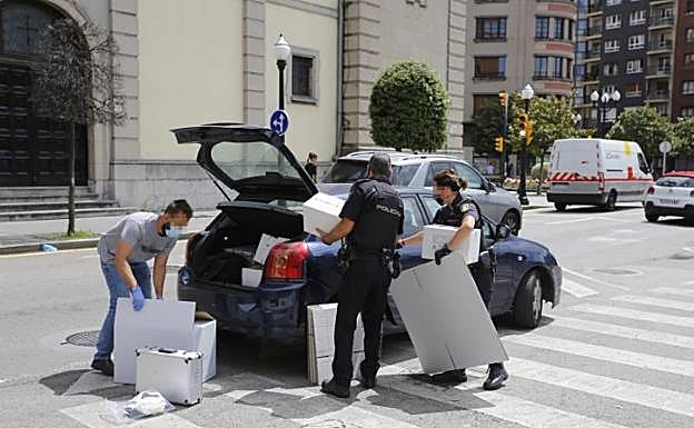 Agentes de la Policía Científica, introducen en un coche cajas con presunto material probatorio de los delitos sexuales cometidos.