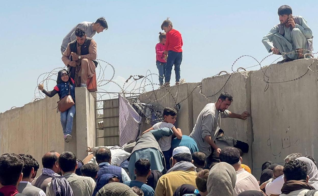 Un hombre ayuda a una mujer a acceder al aeropuerto de Kabul.