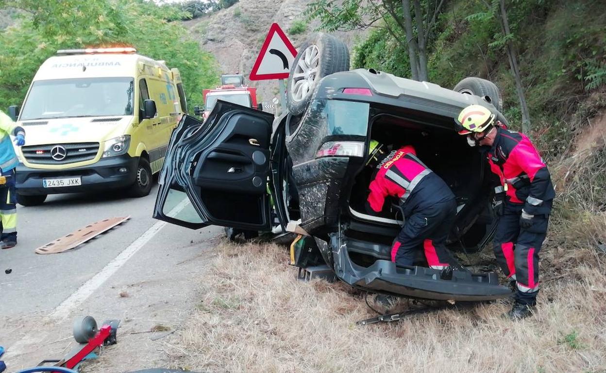Los bomberos trabajan en el vehículo accidentado. 