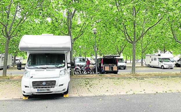 Autocaravana calzada y gente sentada fuera, una práctica no permitida.