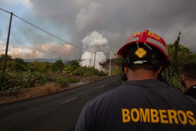 Un bombero observa el humo que se eleva desde la lava que se enfría en Los Llanos de Adirdane.