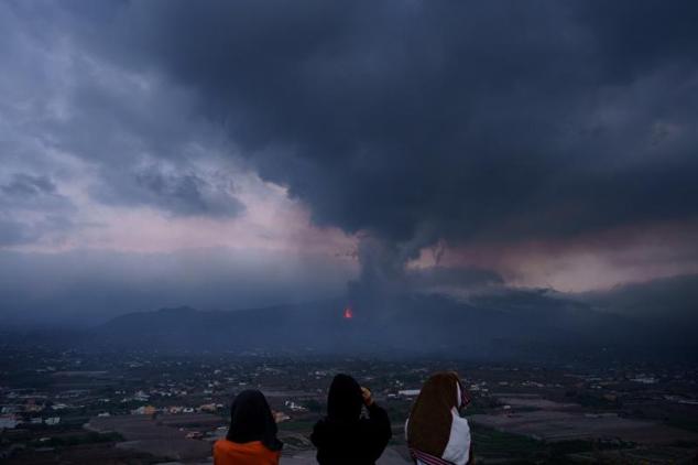 Unas niñas buscan con prismáticos su vivienda en el barrio de El Paraíso, una de las zonas más afectadas por la erupción que tiene lugar en la isla de La Palma.