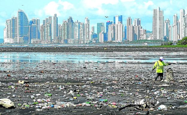 Un hombre recoge basura que ha depositado la marea en la playa Costa del Este, en Ciudad de Panamá. 