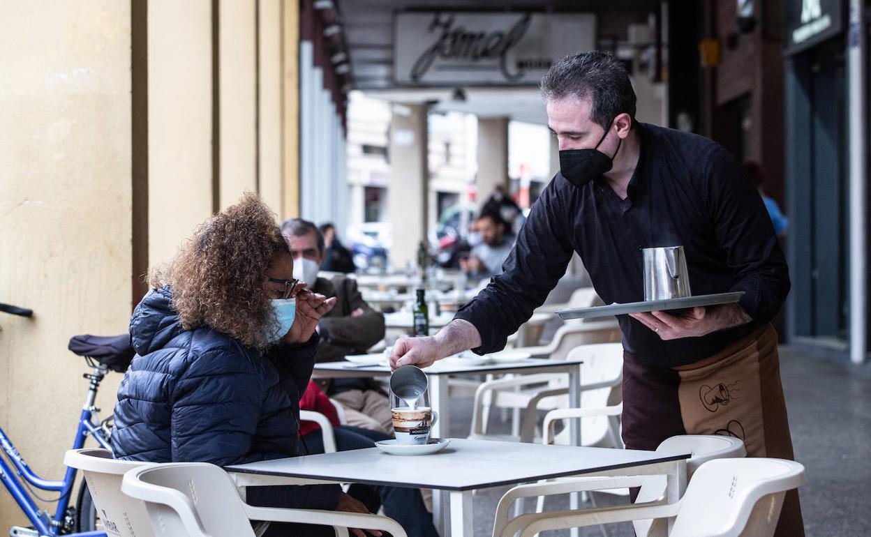 Una clienta tomando un café en la terraza de un bar.