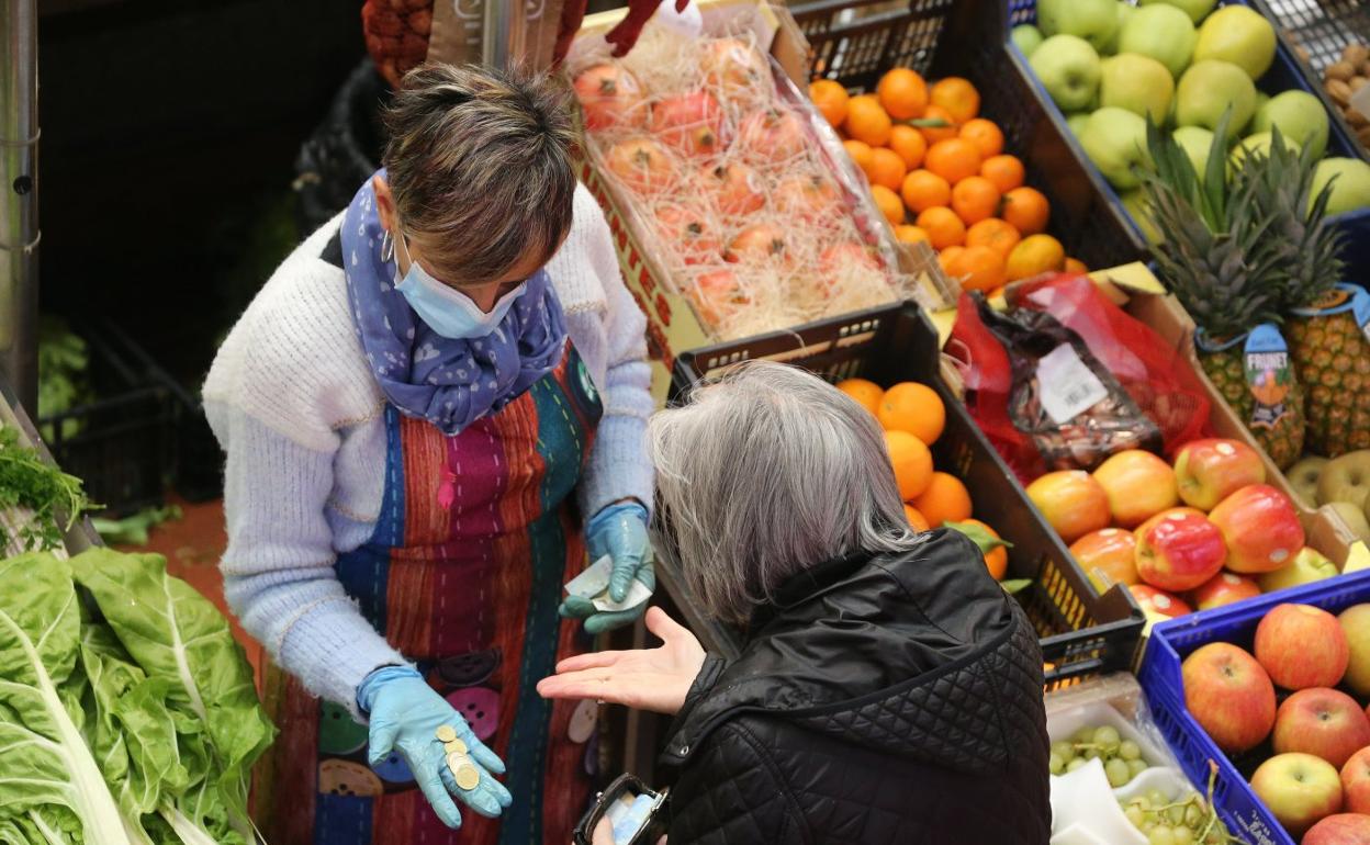 La frutera devuelve el cambio a una clienta en un puesto de la Plaza de Abastos de Logroño. 