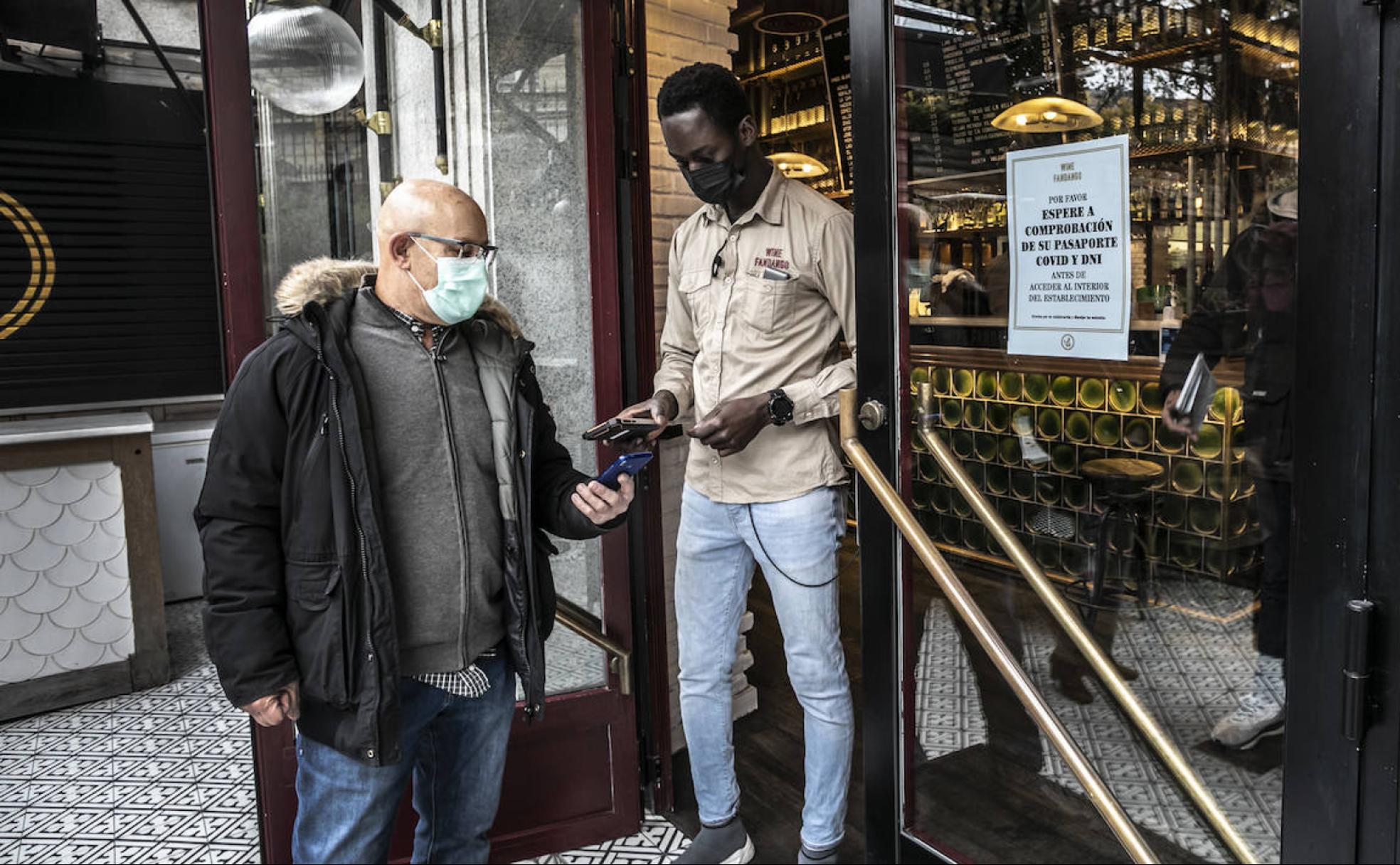 Un empleado del Wine Fandango solicita a un cliente que le muestre el pasaporte COVID antes de acceder al interior del establecimiento.