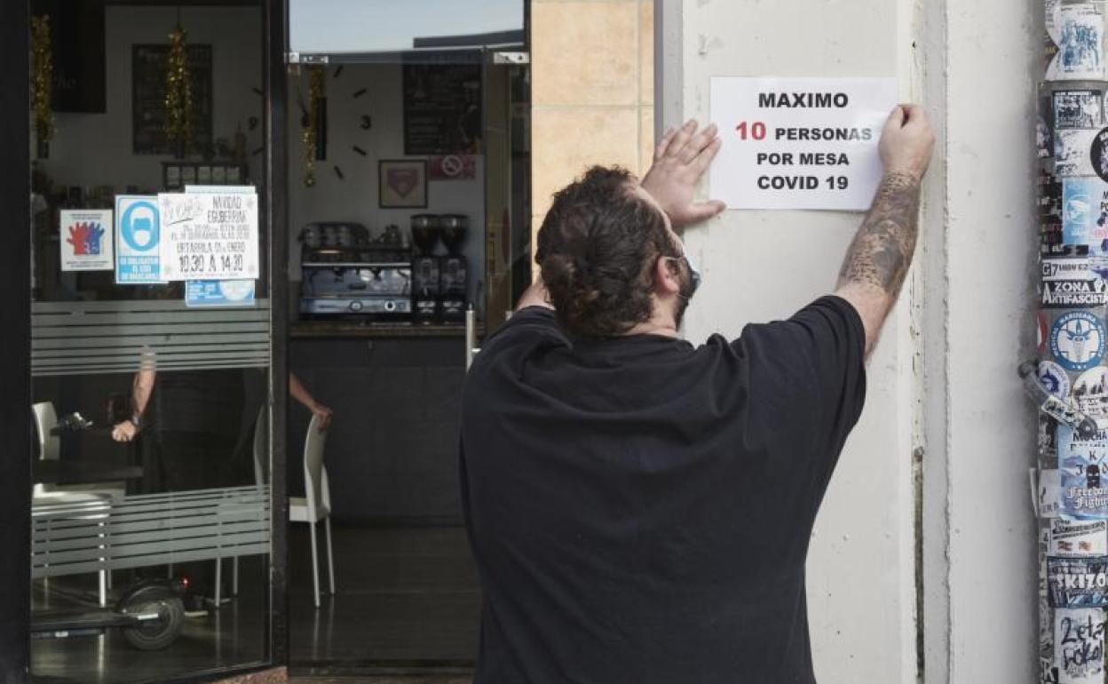 Un camarero coloca un cartel de reducción de aforo en Pamplona.