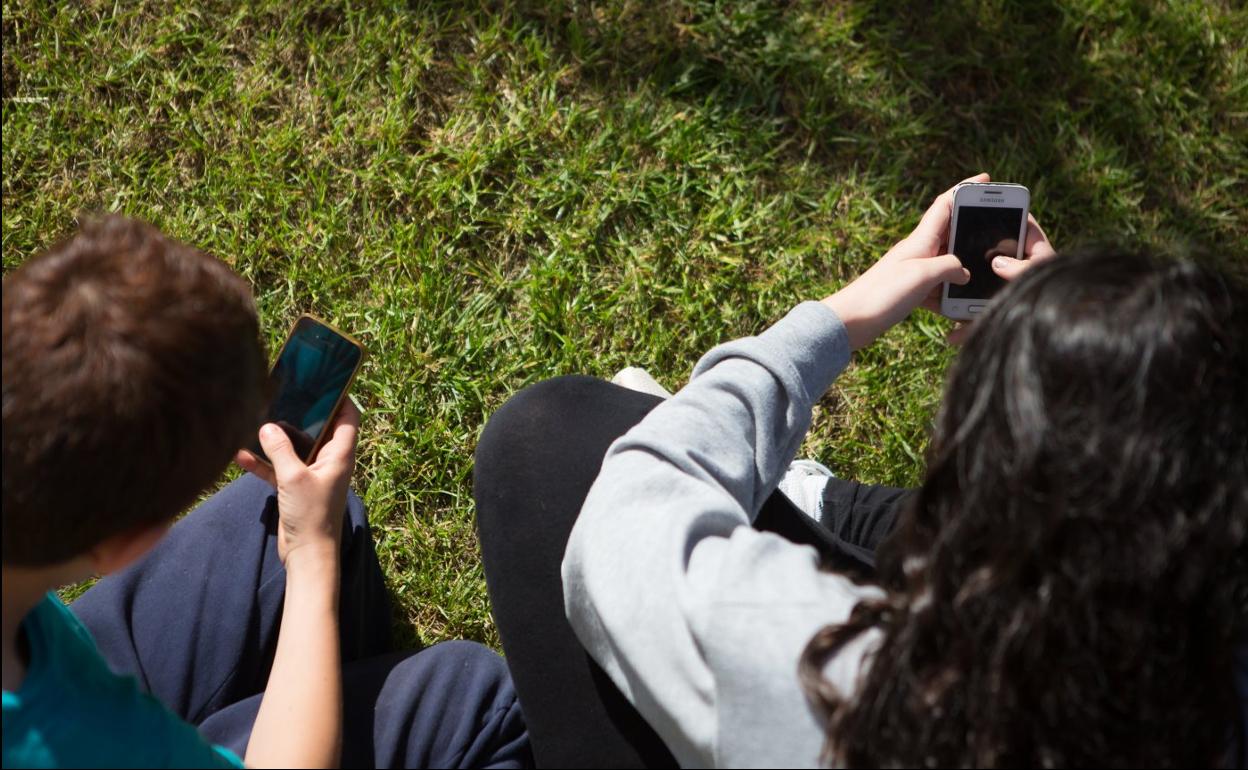 Dos menores de edad navegan por internet a través de sus dispositivos móviles, en una imagen de archivo. 