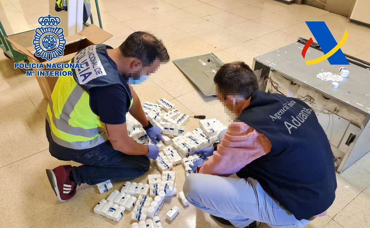 Dos agentes revisan la mercancía decomisada. 