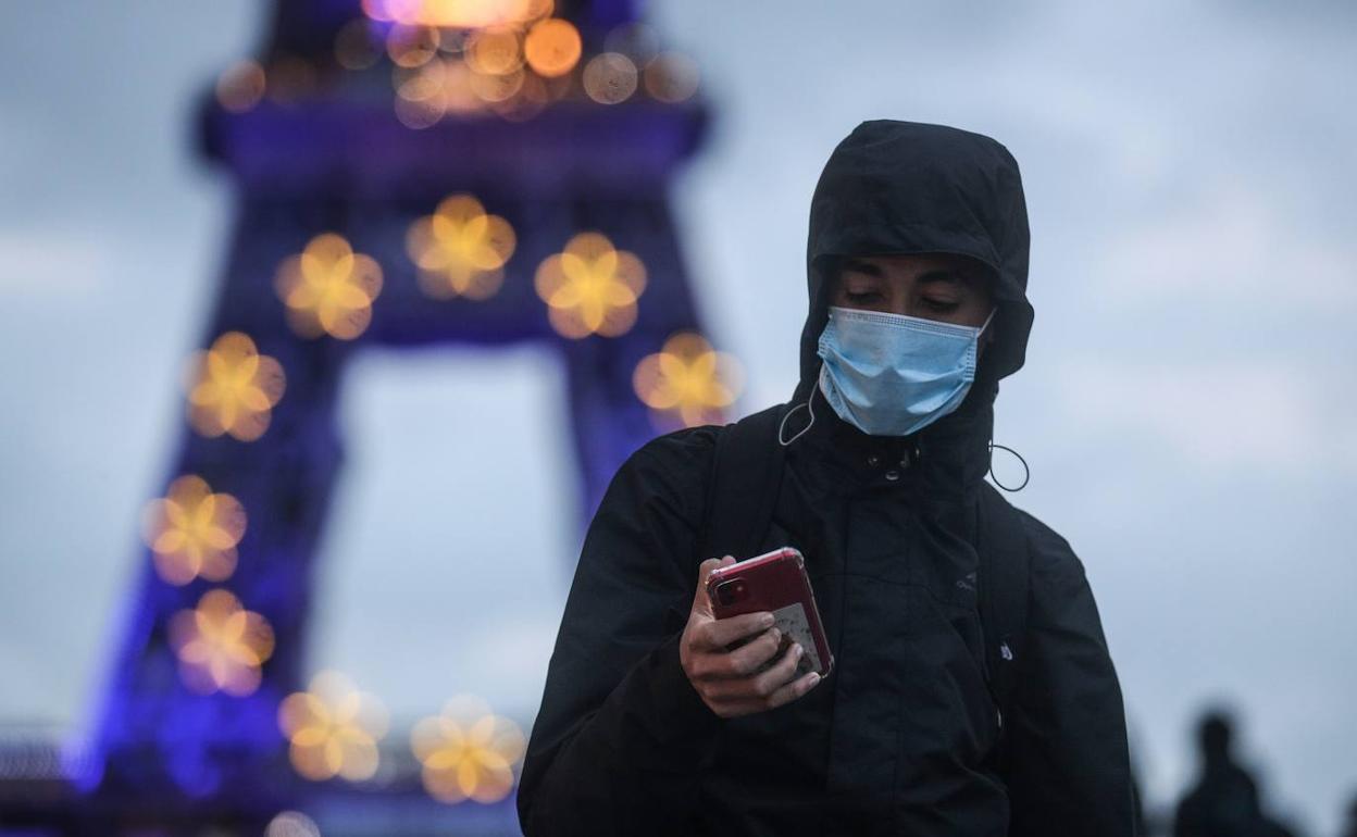 Un hombre pasea frente a la Torre Eiffel en París, con la mascarilla puesta.