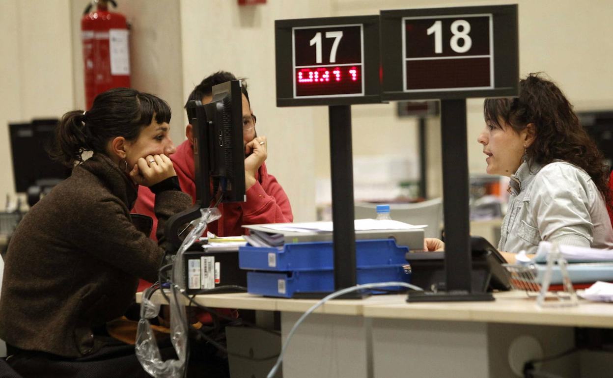 Funcionaria de una oficina del INEM atiende a un par de jóvenes desempleados. 