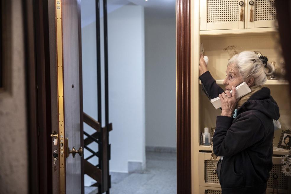 Riesgos. Una mujer mayor habla por teléfono desde la entrada de su casa sin haber cerrado la puerta de entrada al hogar. 