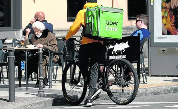 El repartidor de una empresa acude con su bici a recoger un pedido a un bar. 