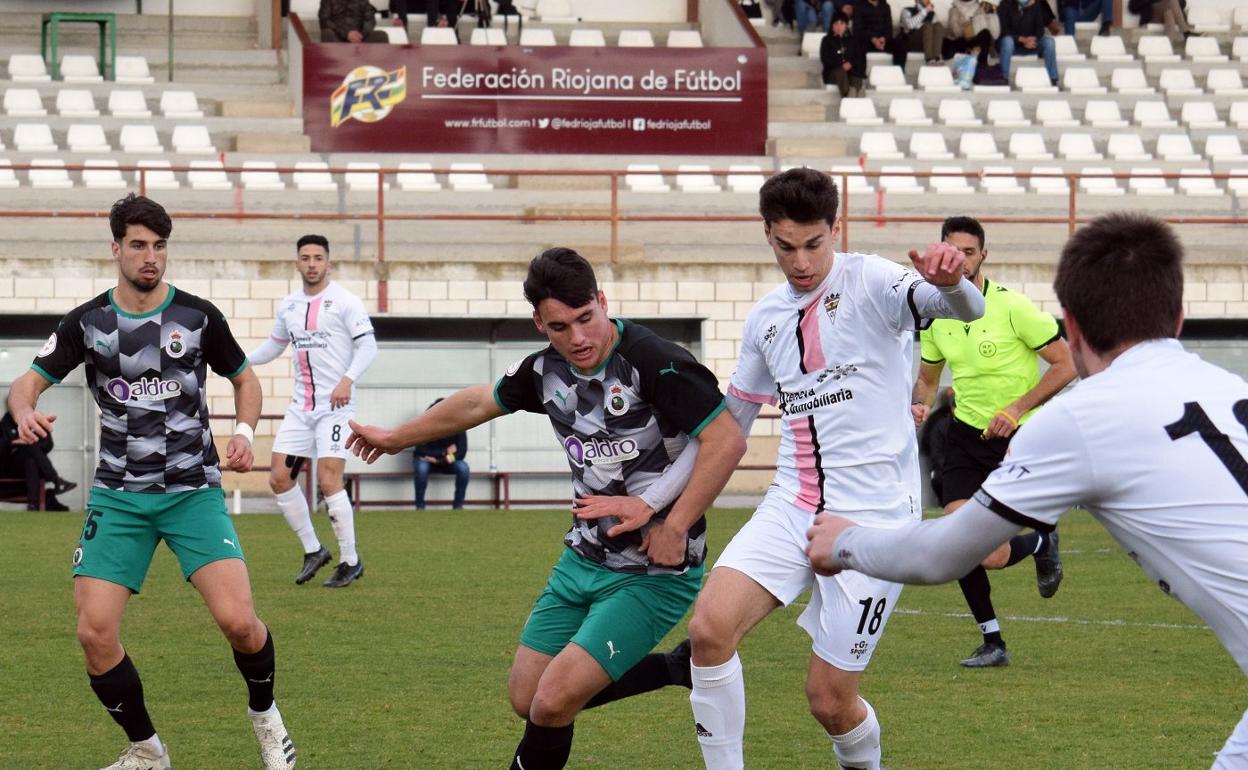 Álvaro controla el cuero en el centro del campo ante la presión de los jugadores del Rayo Cantabria. 