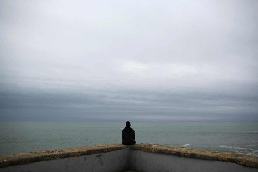 Un joven sentado contemplando el mar. 