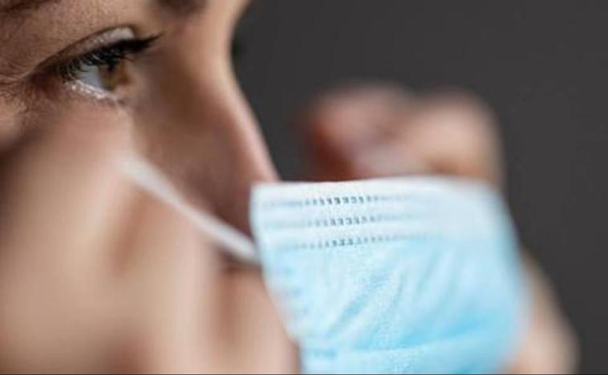 Una mujer se quita la mascarilla. 