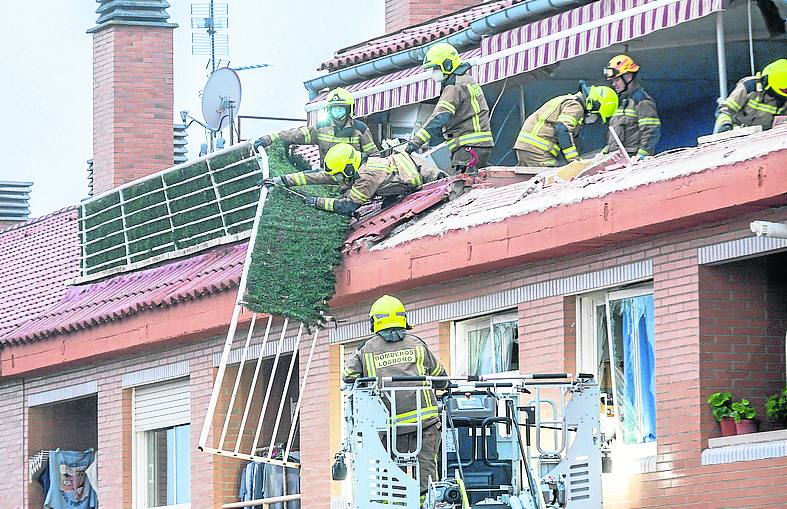 Los bomberos retiran una barandilla de los áticos. 