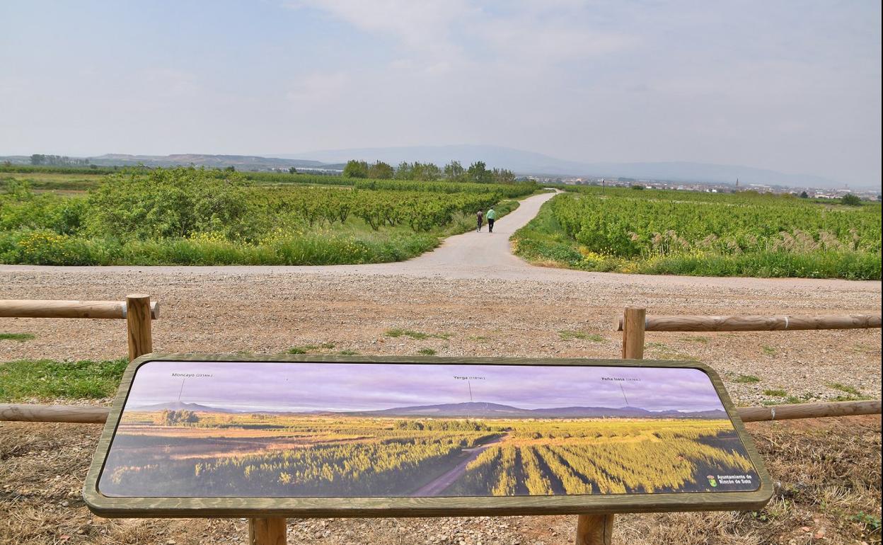 Una de las señales indicativas de las rutas del Ebro y un panel con los cultivos de peras y las cumbres del Moncayo, Yerga y Peña Isasa, al fondo. 