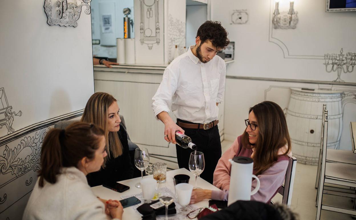 Un camarero sirve una copa de vino a varias mujeres.