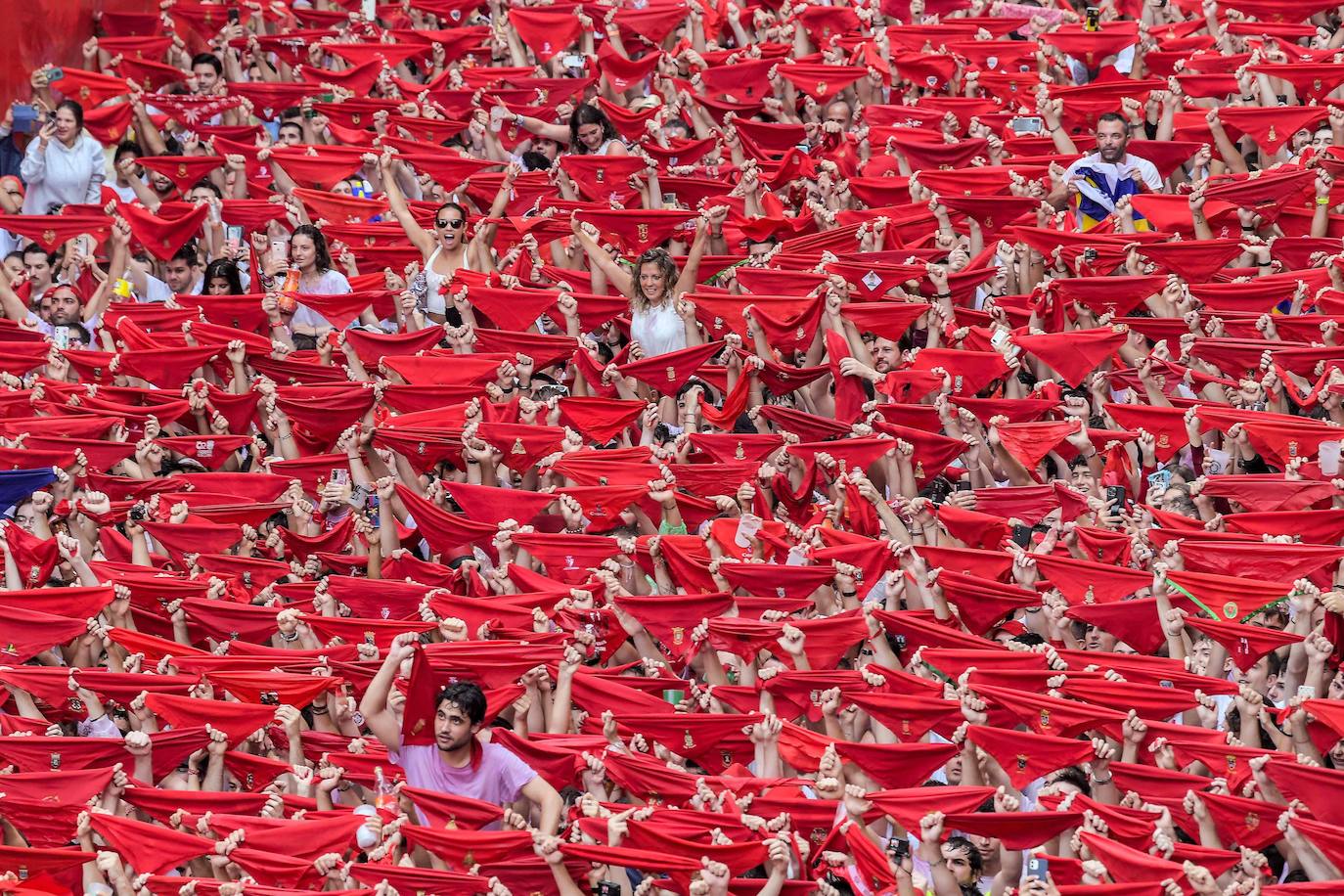 Cientos de mozos y mozas muestran sus pañuelicos rojos antes de atárselos al cuello, una vez que suena el chupinazo. 