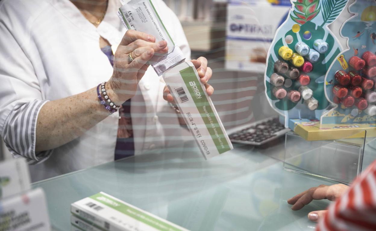 Una farmacéutica dispensa un test de antígenos a una clienta. 