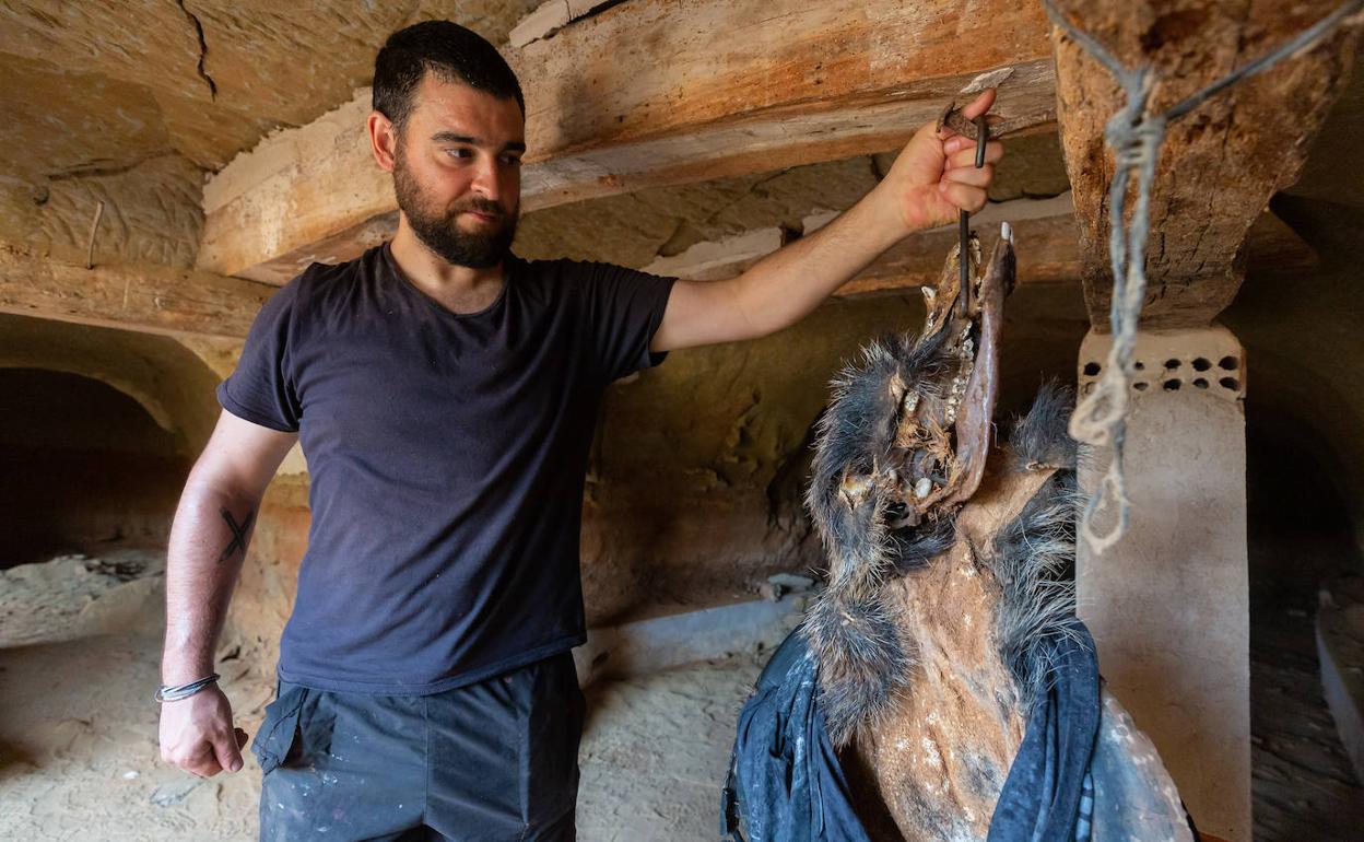 Zorromono, en el monasterio rupestre, sujetando una piel de jabalí que empleará en su obra.