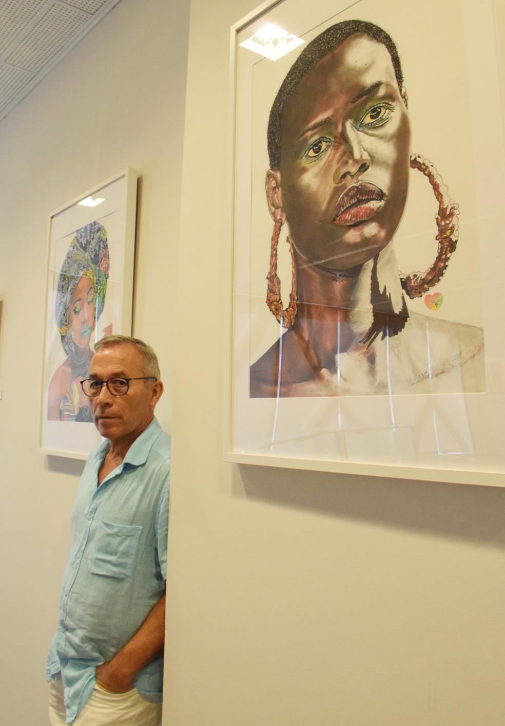 Pedro Antonio Martínez Pavía entre algunos de los retratos de mujeres africanas que protagonizan su exposición en la sede de la AITIR. 