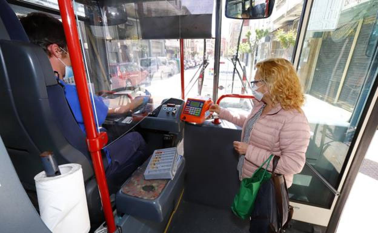 Una pasajera accede a un autobús protegida con una mascarilla. 