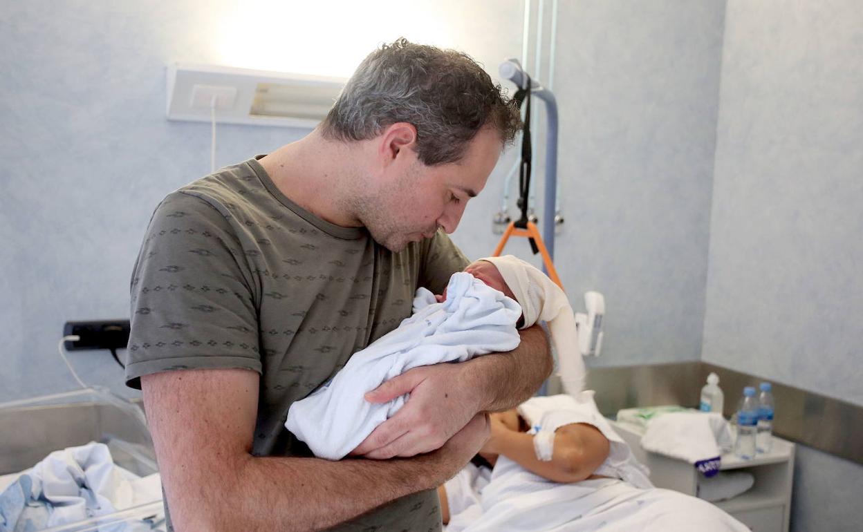 Un padre sostiene a su hijo recién nacido. 