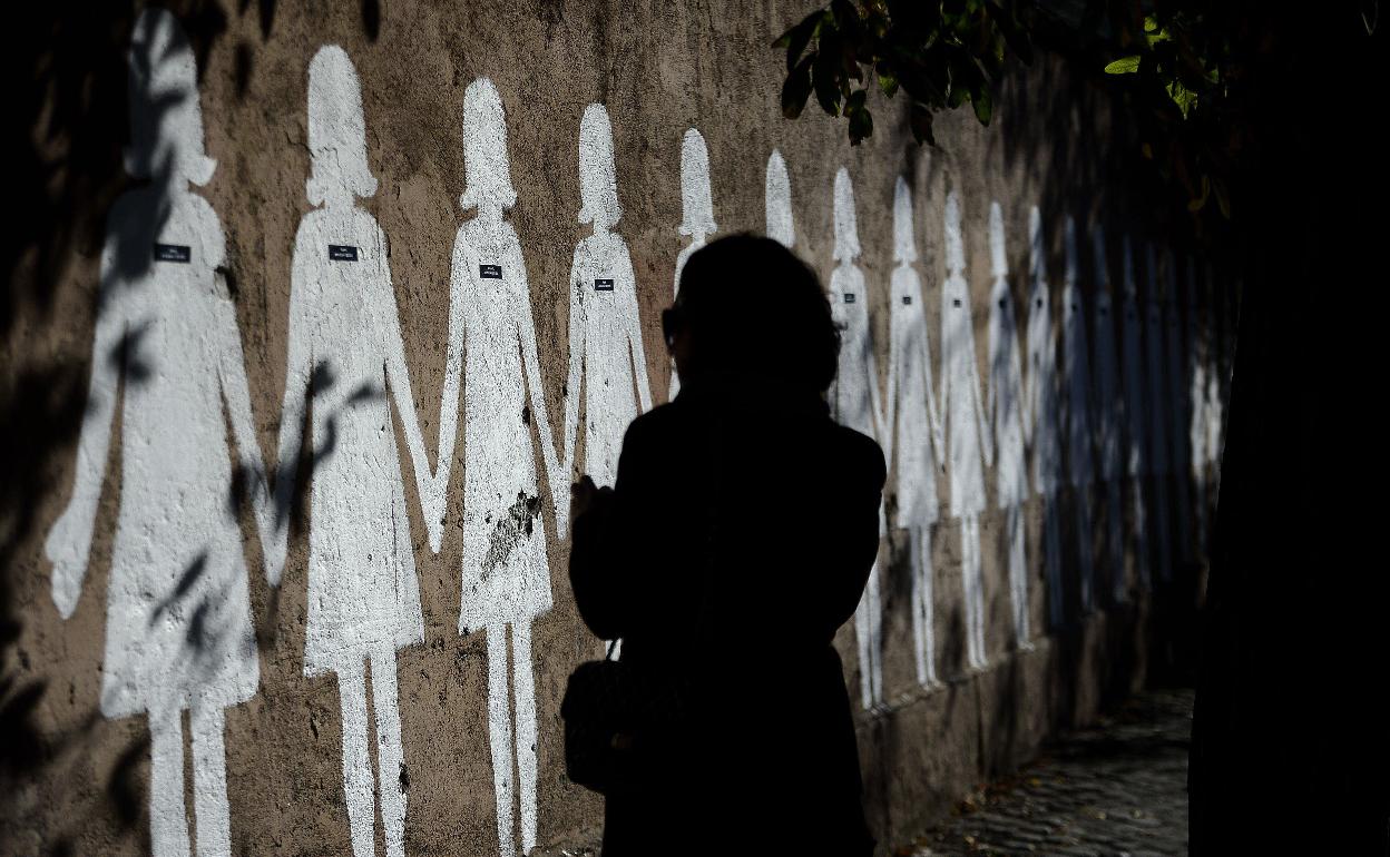 Mujer frente a siluetas blancas representando víctimas de violencia de género