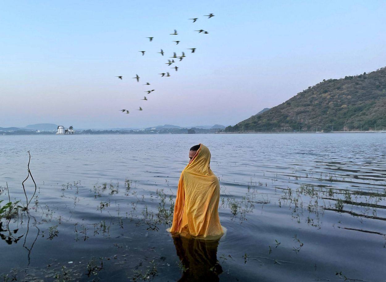 Un hombre parado en agua helada esperando que llegue el Dios Sol durante el Festival Chatth Puja